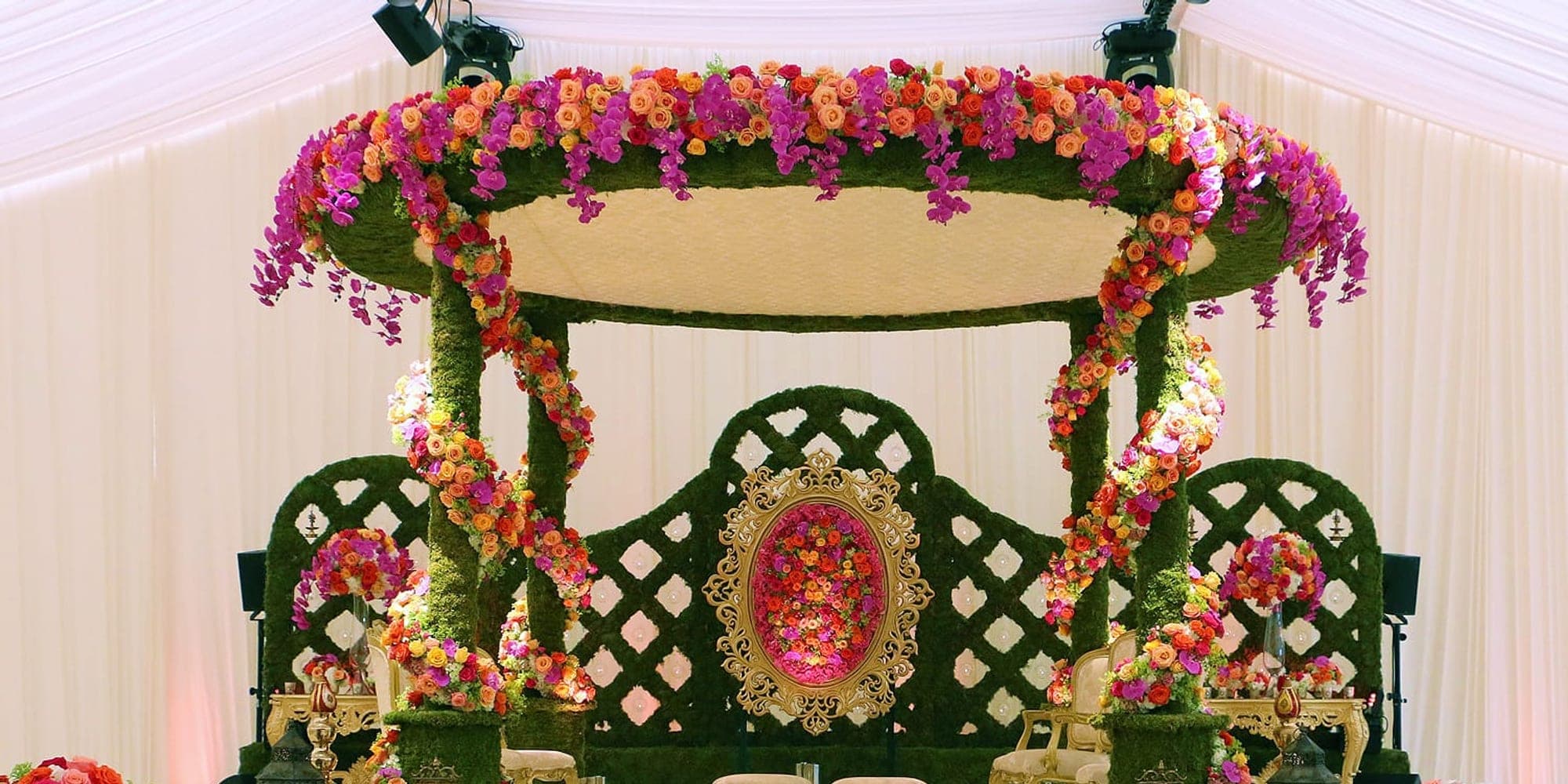 Colourful pink, orange and green floral mandap with a lattice backdrop