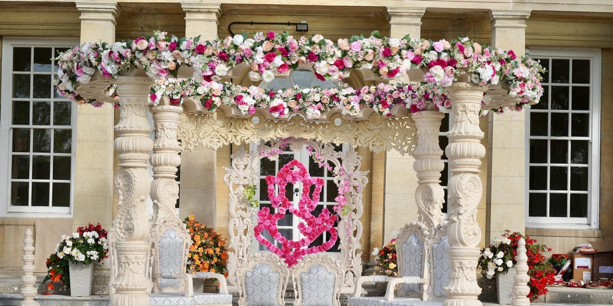 Carved cream stone pillar mandap with a floral canopy and Ganesh design