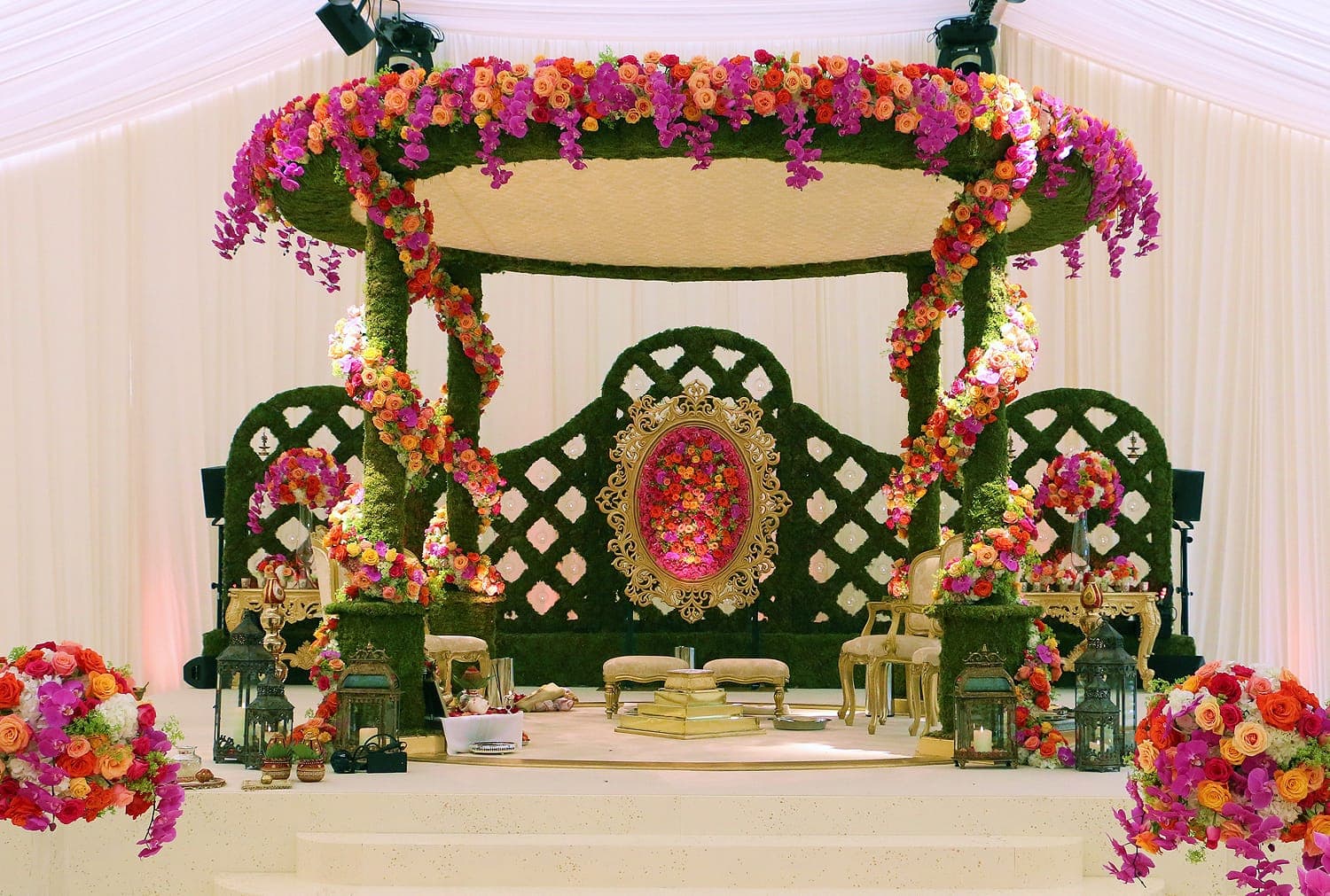 Moss round mandap with magenta and orange flowers spiralling around pillars