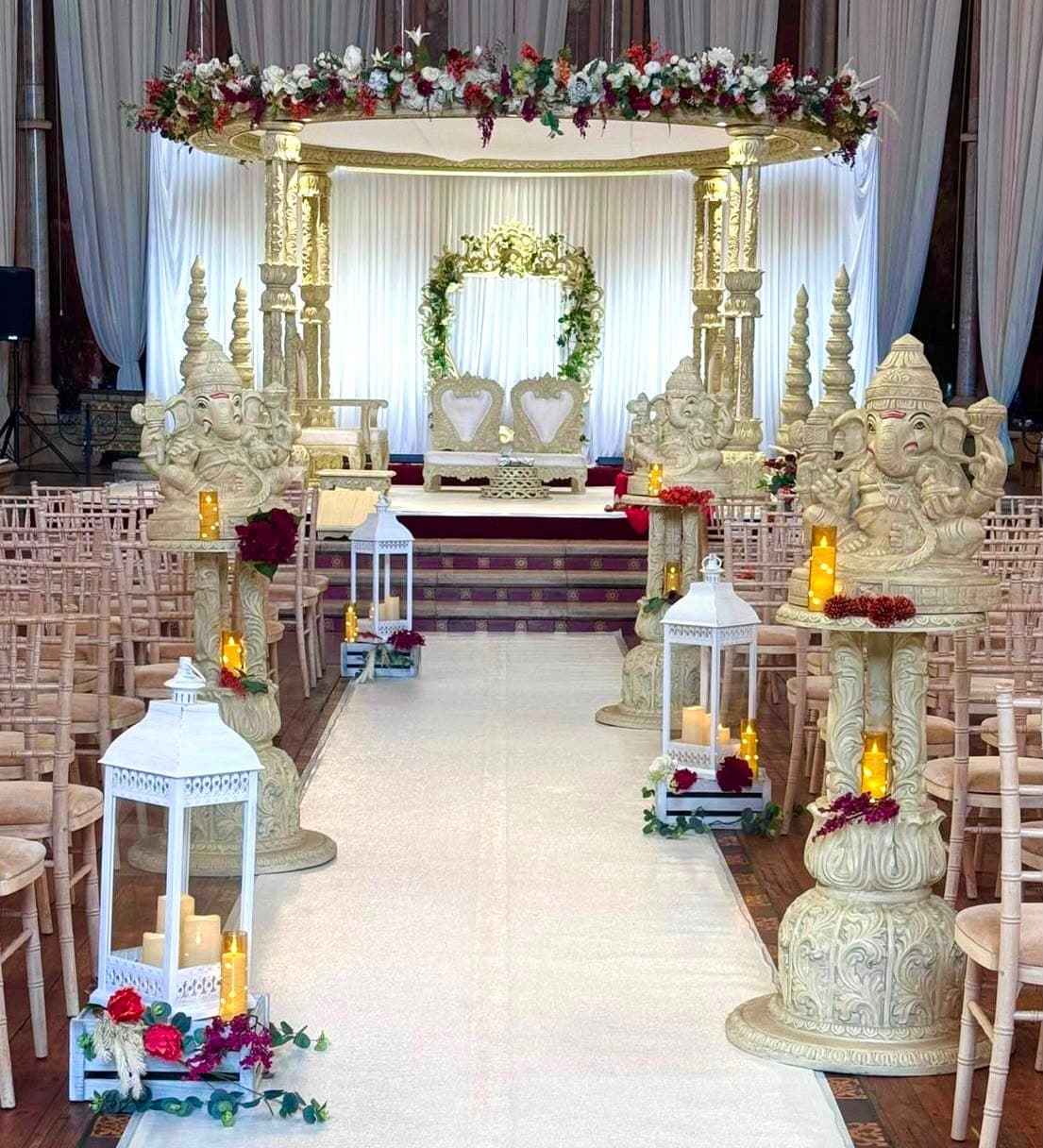 Ivory round canopy on carved pillars with a floral arch and lanterns on a stepped stage
