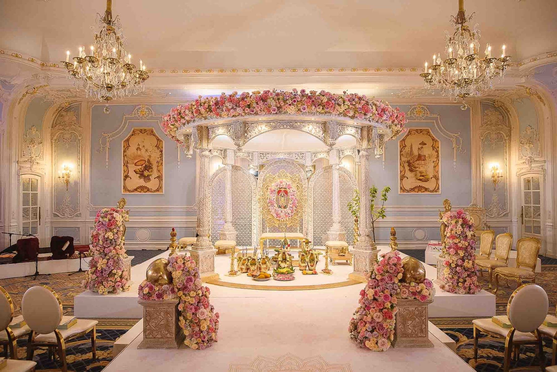 Ivory round canopy with pink rose ring in a chandelier-lit blue ballroom