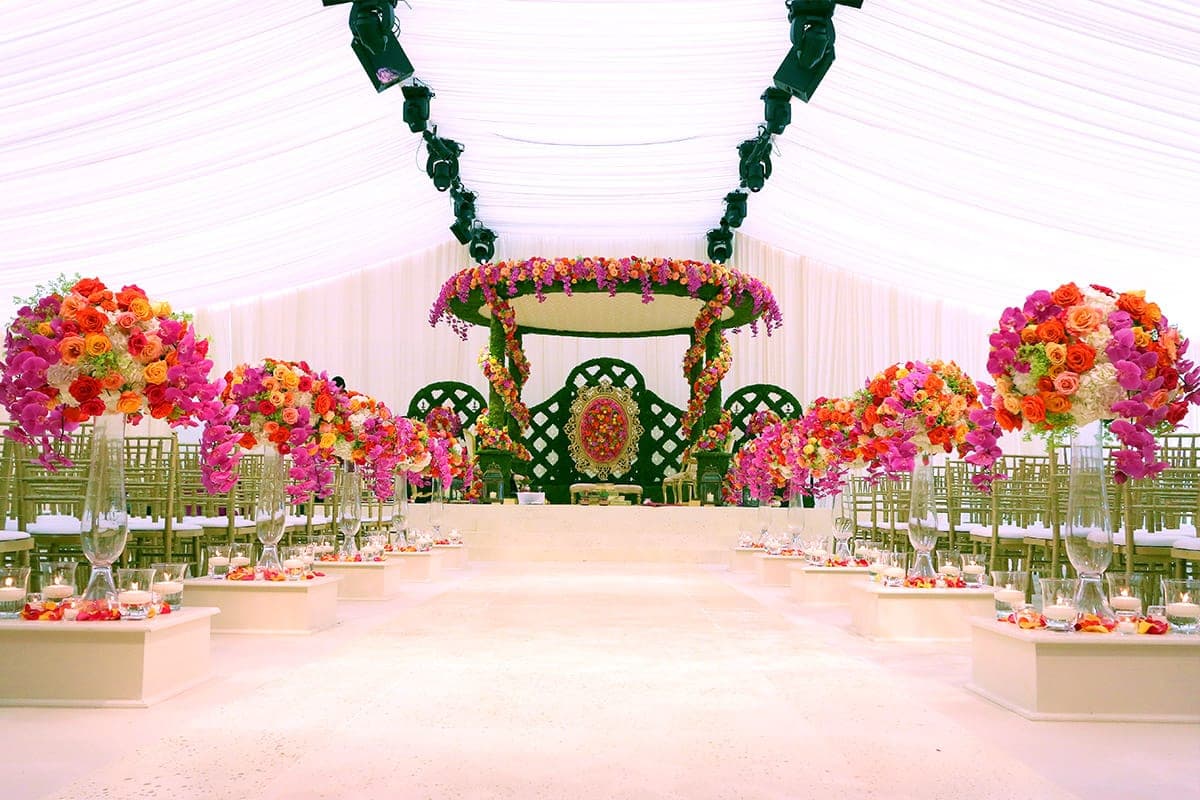 Foliage-covered round canopy with green lattice backdrop in a white marquee
