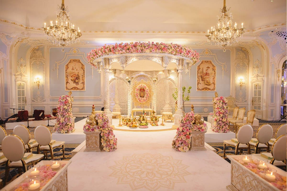 White domed lattice mandap with pink rose ring in a pale blue ballroom