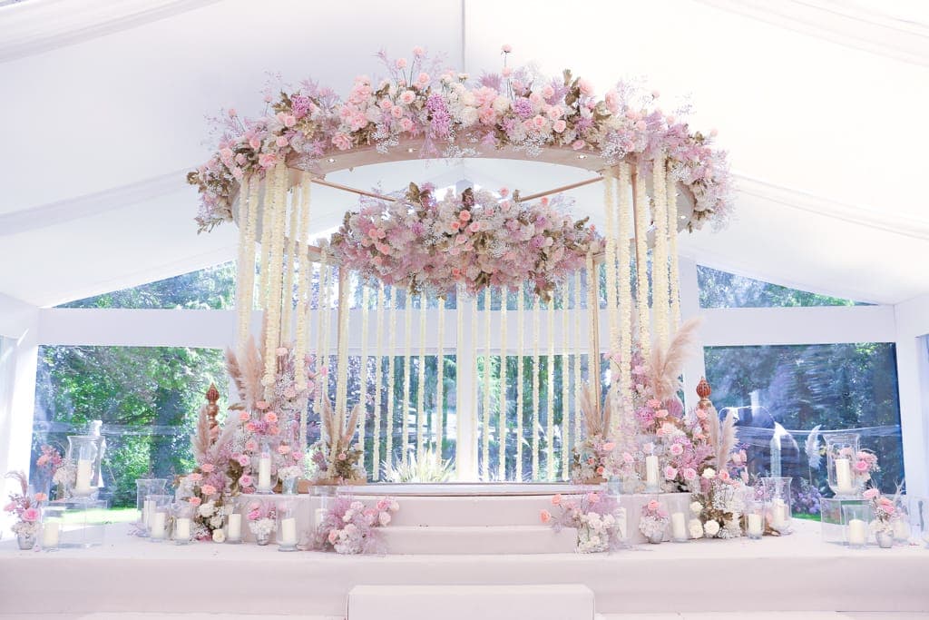 Pale pink floral crown over white strands and pampas grass in a white marquee
