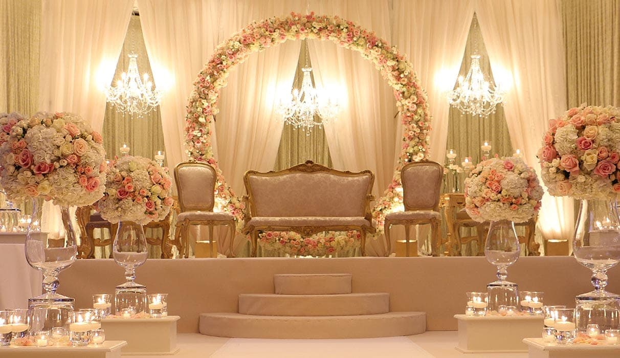 Floral ring mandap with gilt sofa and rose bouquets in a candlelit hall