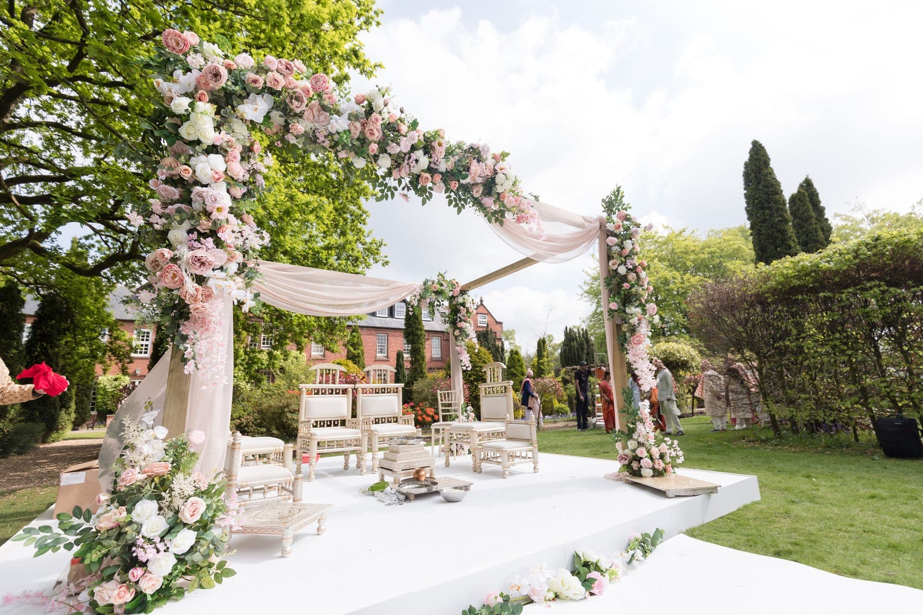 Blush and ivory floral arch with chiffon over a white deck on a lawn