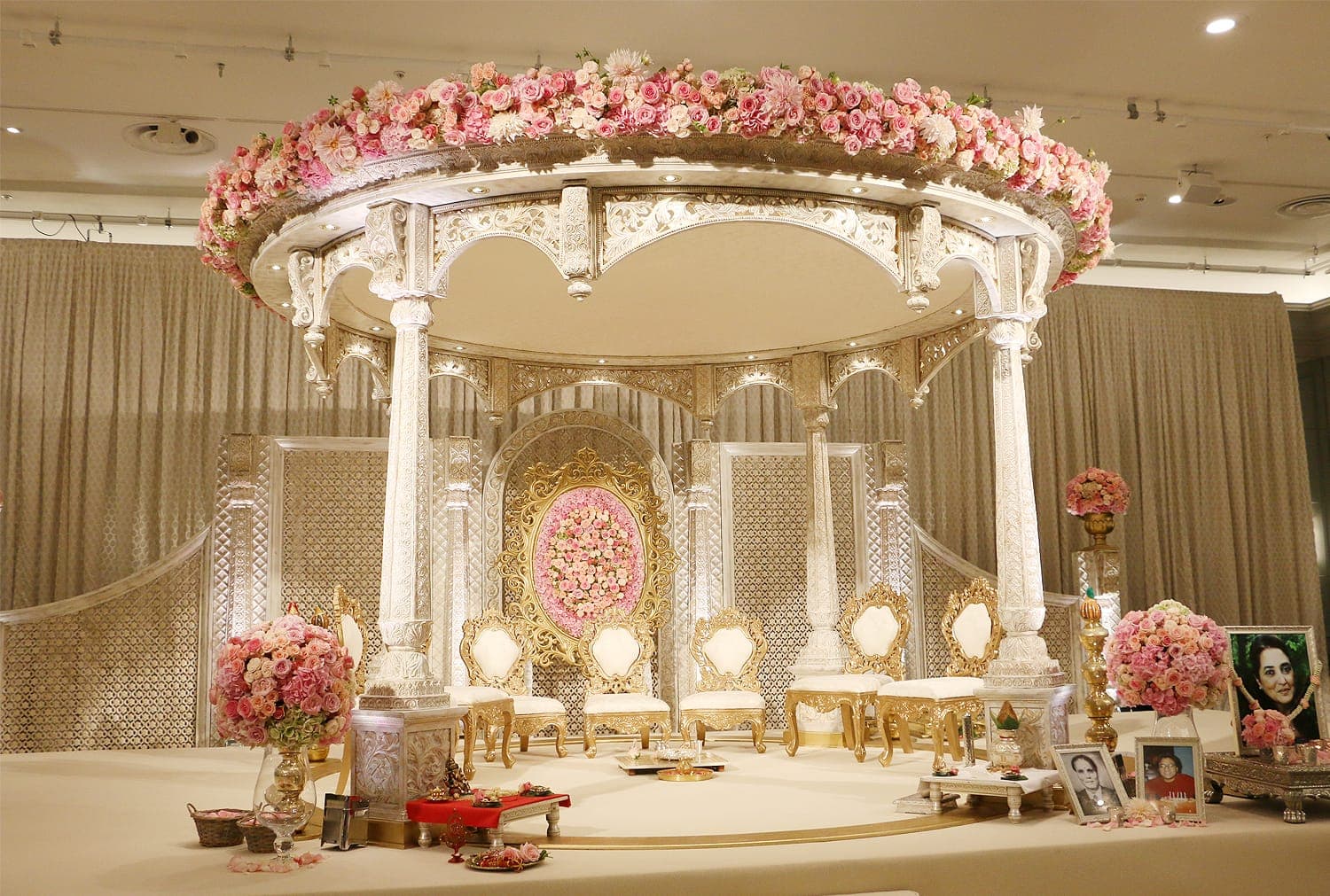 White carved round mandap with pink rose rim and gold oval frame backdrop