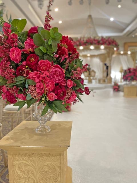 Prince mandap with red rose canopy and white aisle in a hall