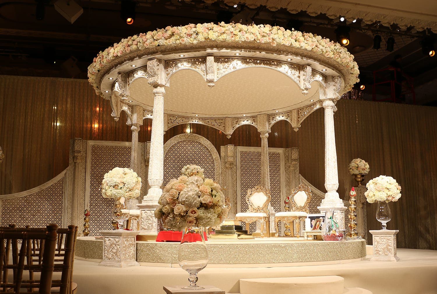 White carved round canopy with cream and blush rose ring and gold chairs