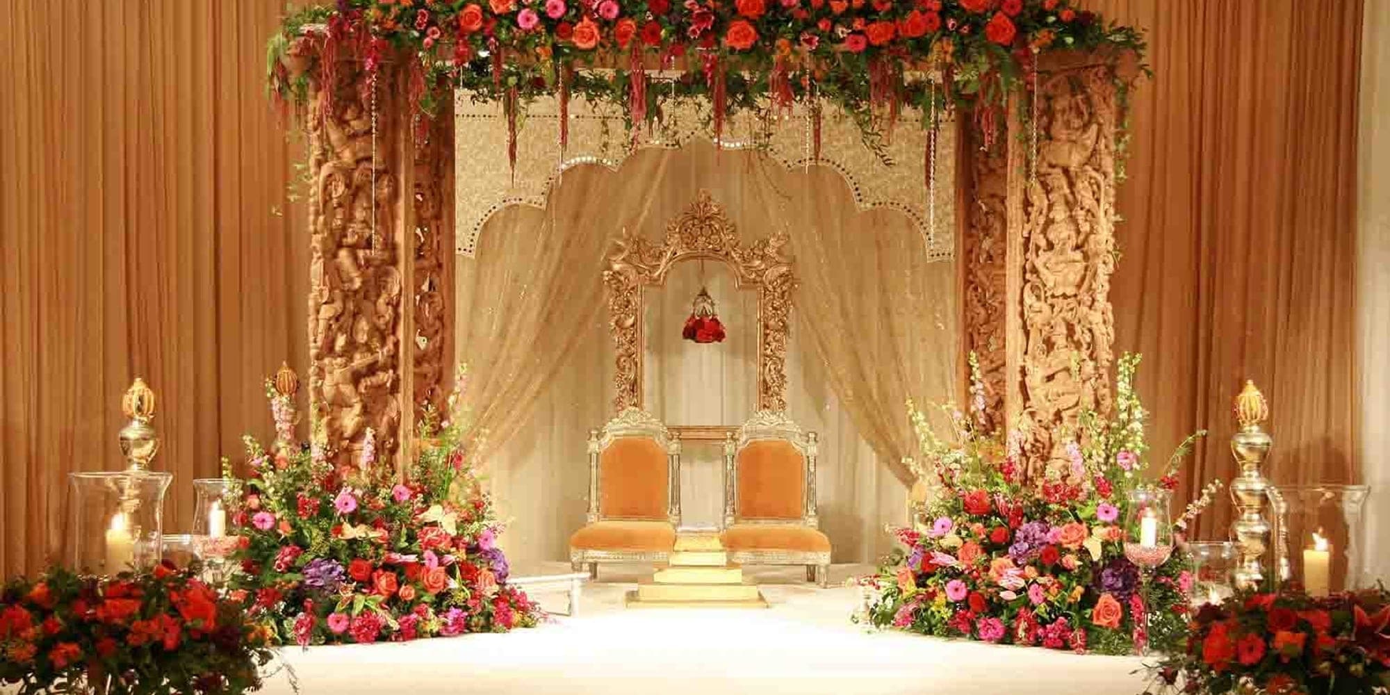 Mandap Hire Agreement Checklist: What It Should Say Orange wooden carved mandap with a floral top and a throne chair
