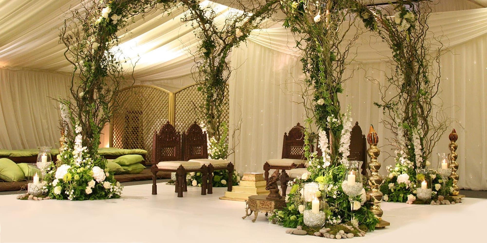 Mandap Hire Problems and How to Avoid Them Foliage arches in a lined marquee with carved wooden seats