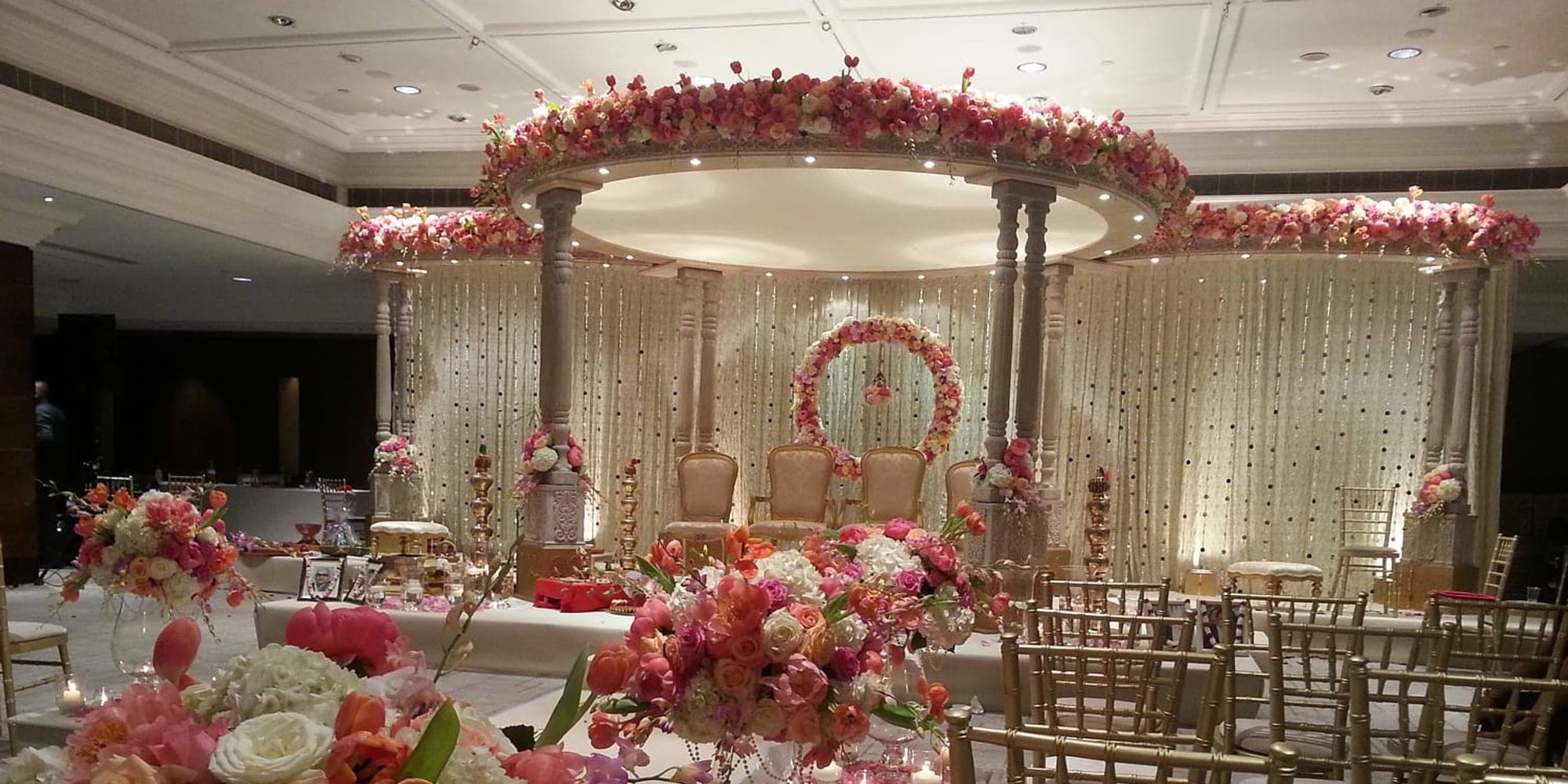 Mandap Planning Timeline: 12 Months to Your Wedding Red floral canopy mandap in a hotel room with rows of gold chairs
