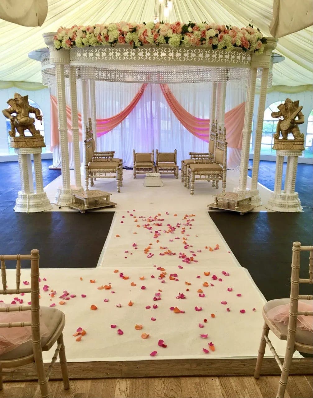 White pillared oval mandap with crystal beads and coral drapes inside a marquee White pillared oval mandap with crystal beads and coral drapes inside a marquee