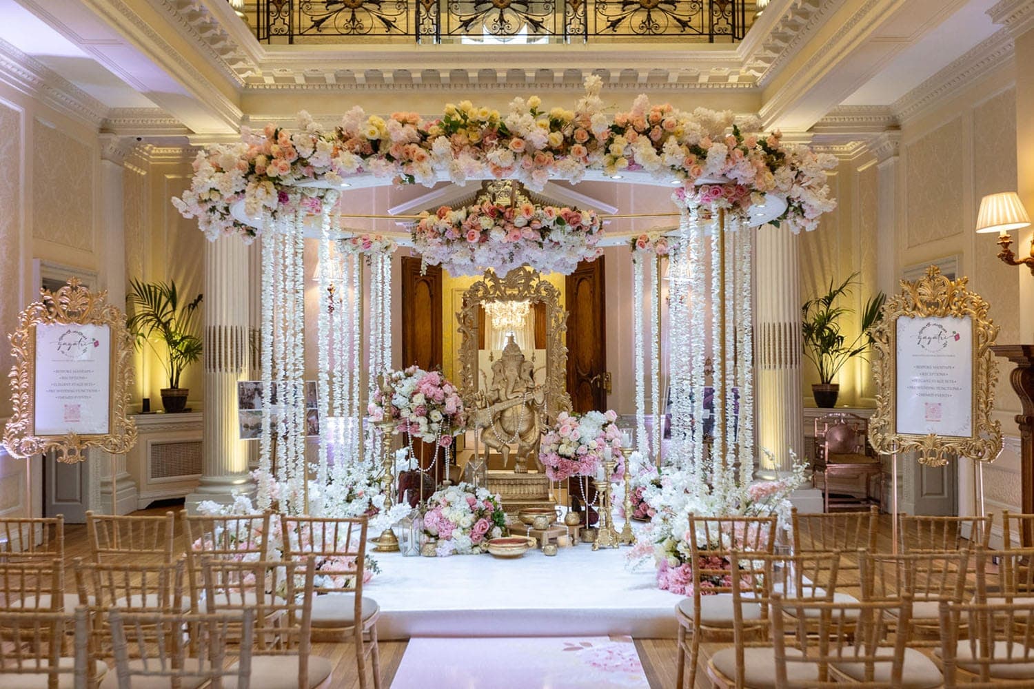 Gold poles with hanging white flower strands around a golden Ganesh in a grand hall Gold poles with hanging white flower strands around a golden Ganesh in a grand hall