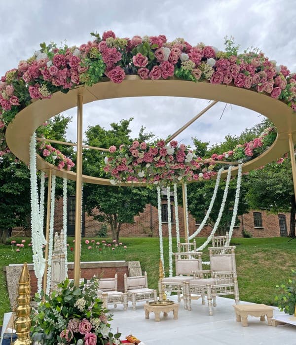 Gold ring mandap with pink roses and white garlands on a lawn Gold ring mandap with pink roses and white garlands on a lawn