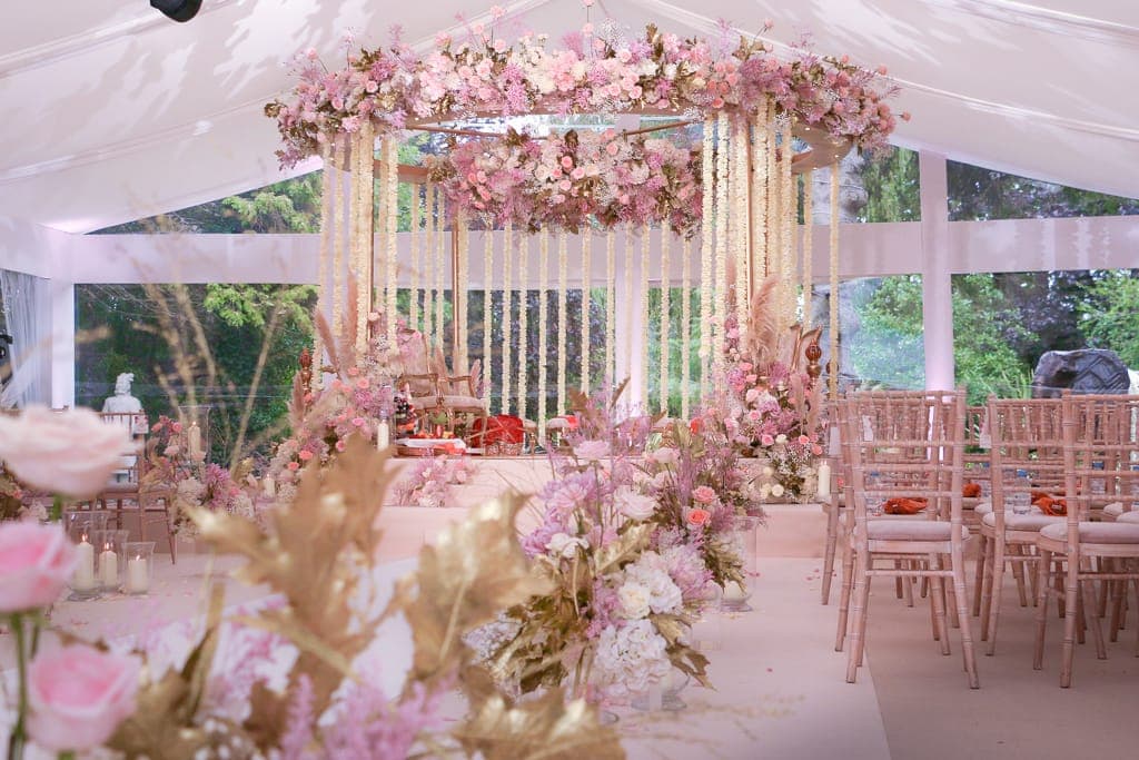 Round wooden frame with pink flowers and hanging white strands in a glass marquee Round wooden frame with pink flowers and hanging white strands in a glass marquee