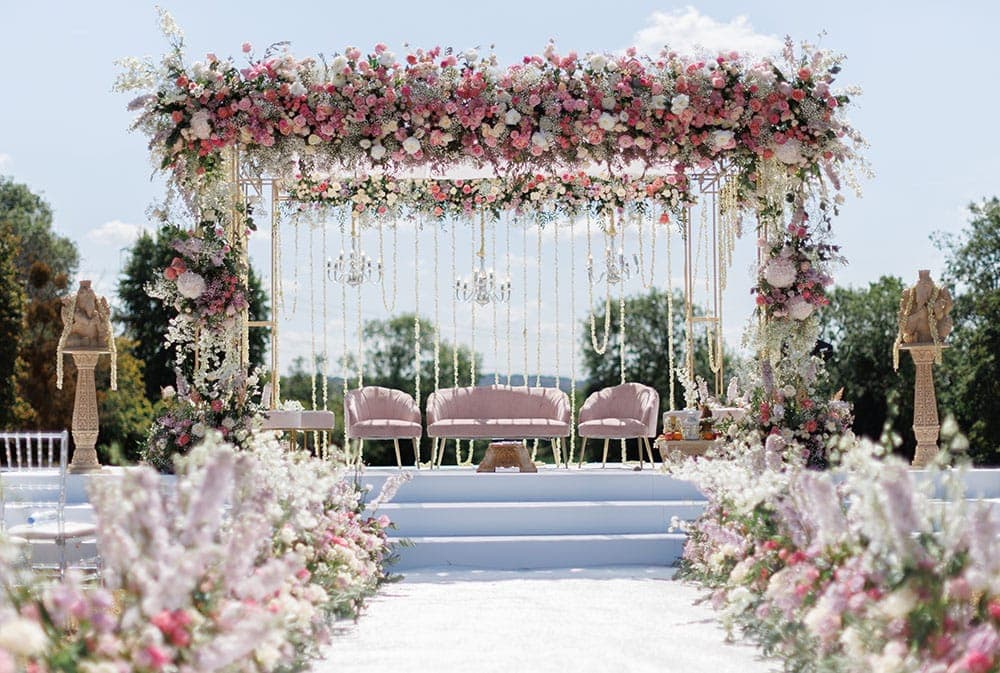 Gold frame with chandeliers, pink roses and blush sofa on white steps beneath blue sky Gold frame with chandeliers, pink roses and blush sofa on white steps beneath blue sky