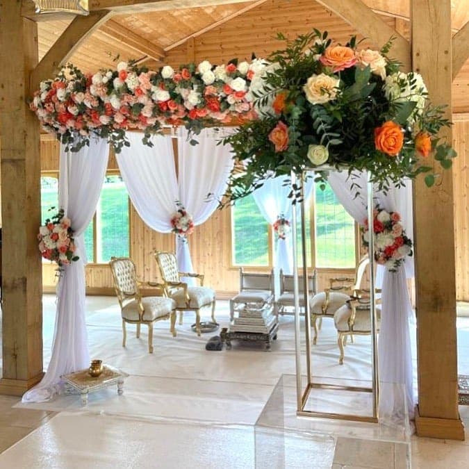 Oak pavilion with white voile drapes and orange peach rose beam in a barn Oak pavilion with white voile drapes and orange peach rose beam in a barn